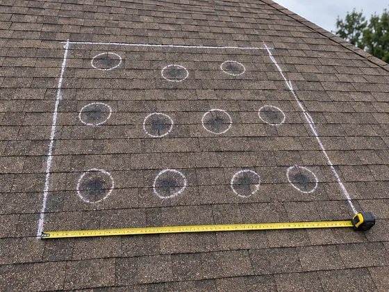 A chalk test square on the hail-hit west slope, each bruise circled and a tape measure along the edge
